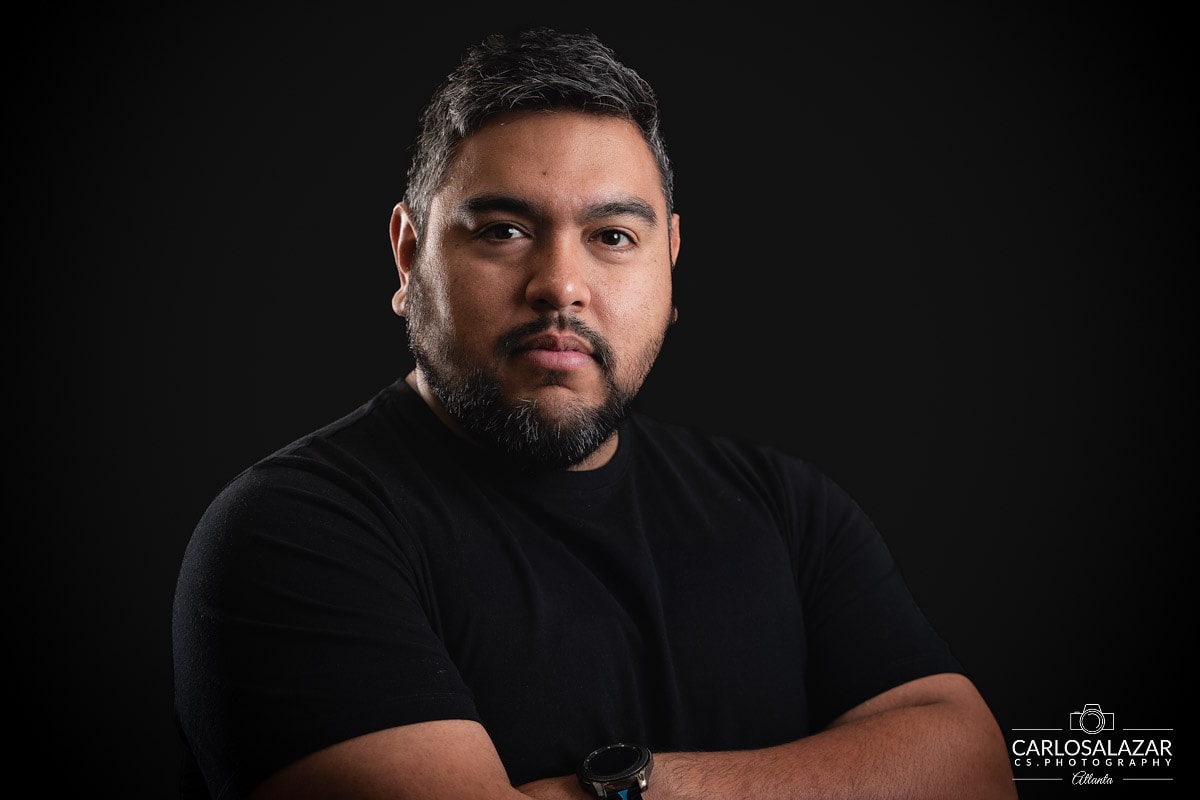 Bearded man in professional portrait with a black t-shirt against a dark background.